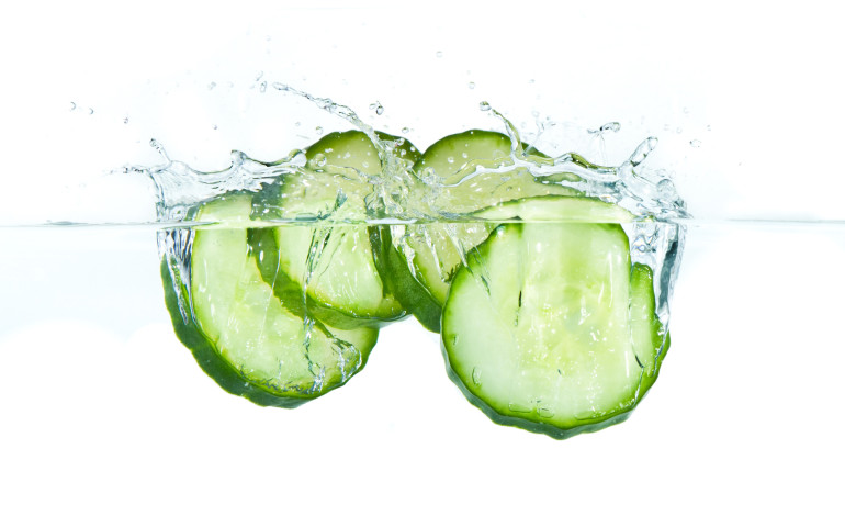 sliced cucumber splashing water isolated on white background